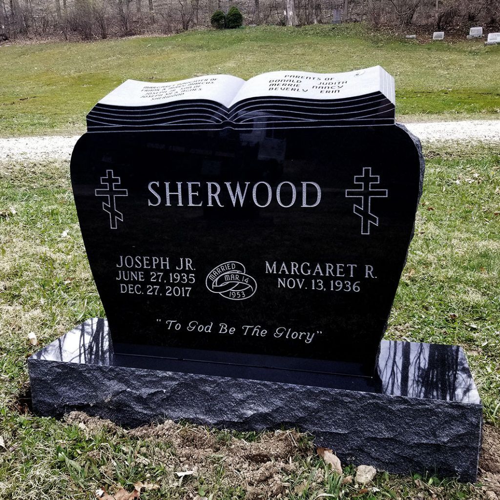Black Sherwood gravestone with open-book top in a grassy cemetery
