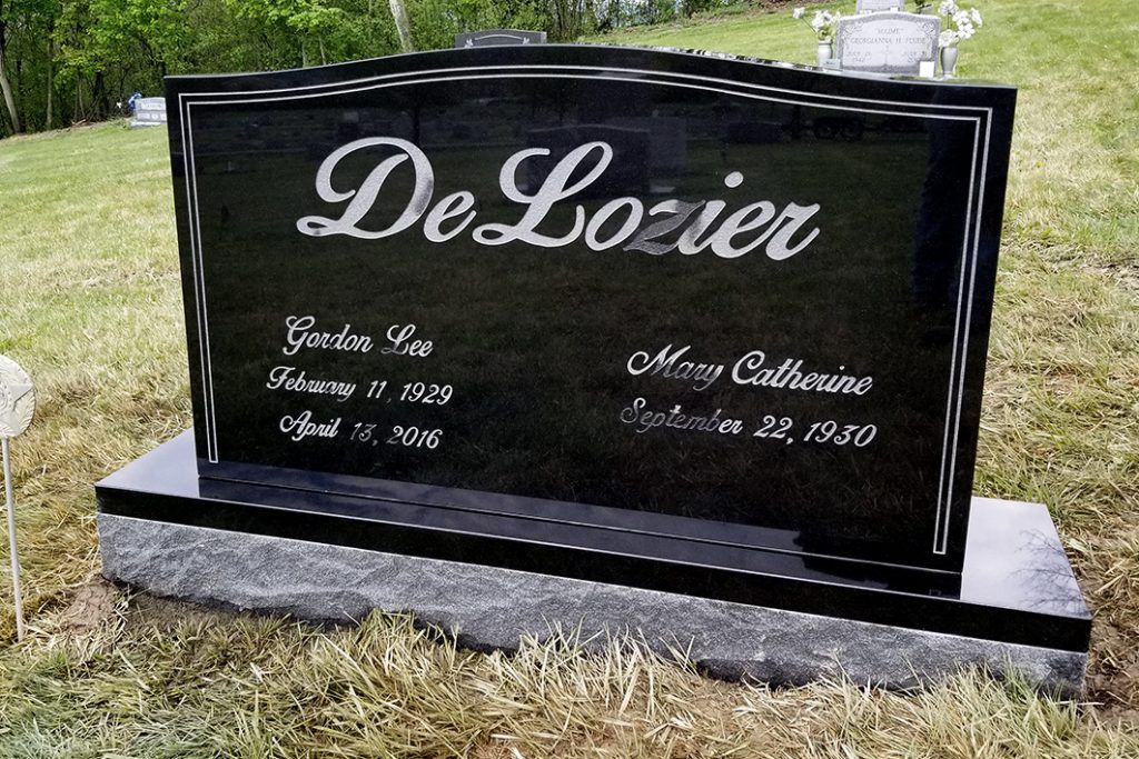 Black granite DeLozier family headstone in a grassy cemetery, with engraved names and dates.