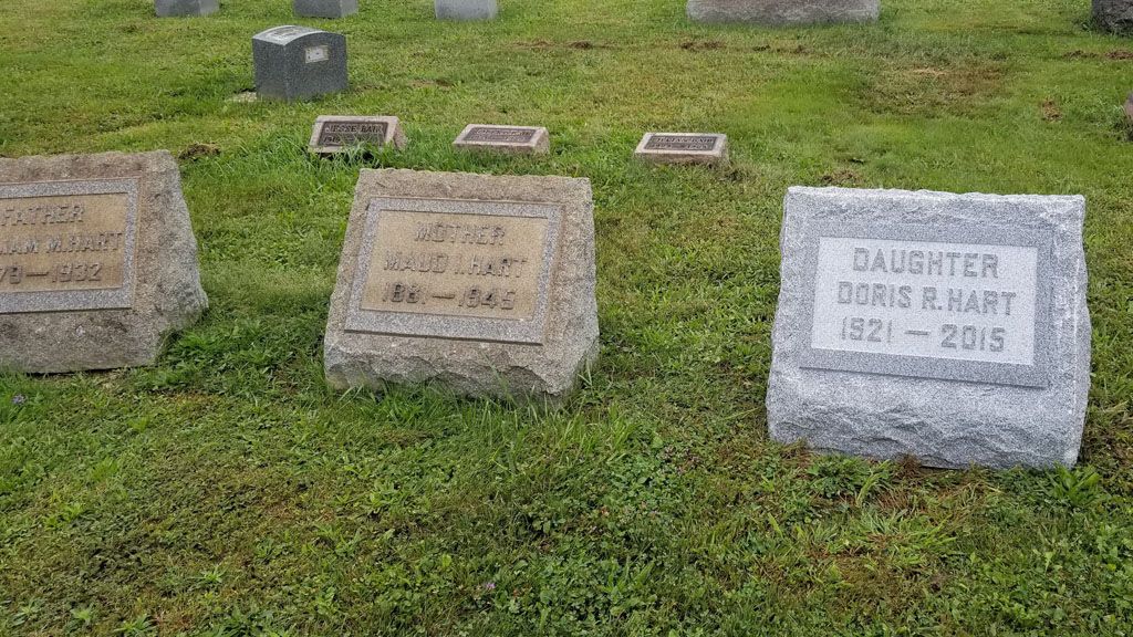 Gravestones in a grassy cemetery, including a headstone for Doris Hart on the right.