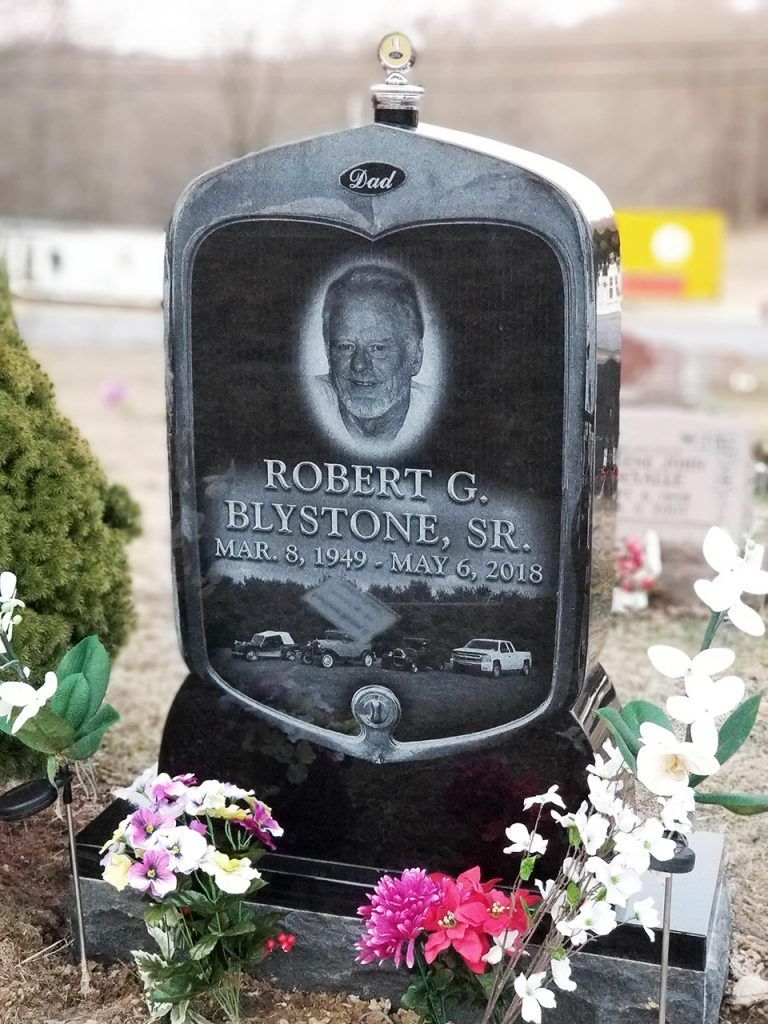 Black granite memorial gravestone with flowers at its base, engraved with the name Robert G. Bystone, Sr.
