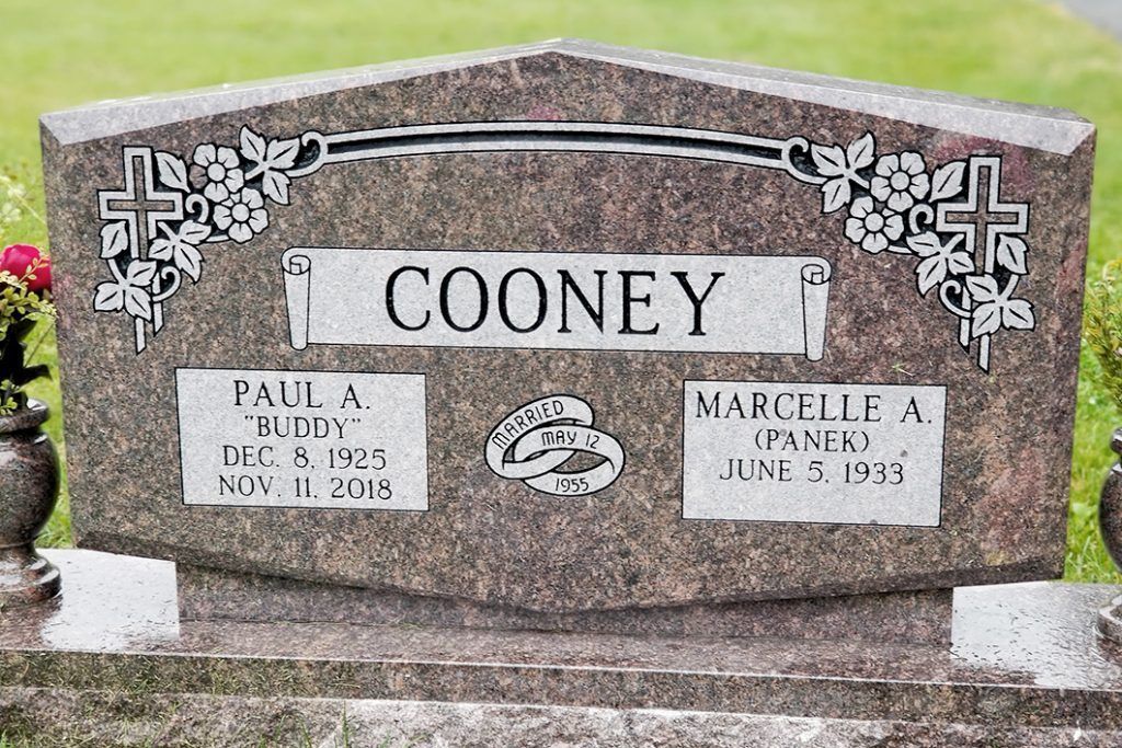 Gray COONEY gravestone with floral engraving and two memorial plaques in a cemetery