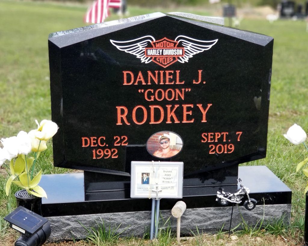 Black gravestone with wings and flowers, engraved