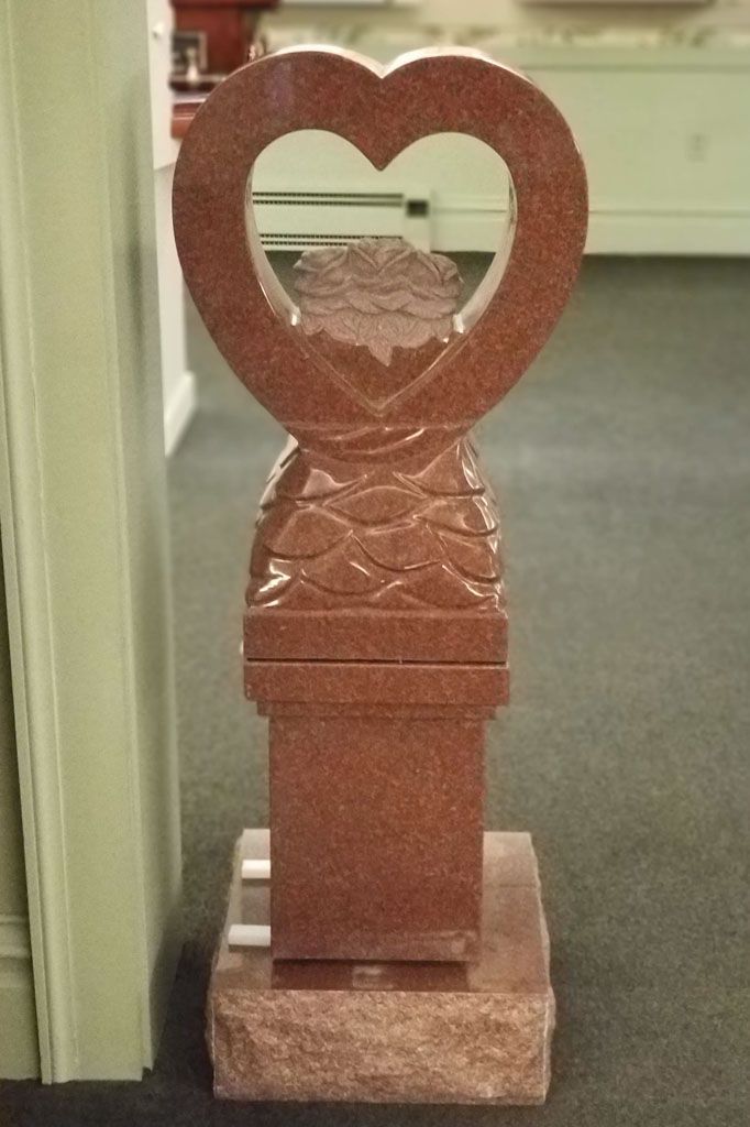 A brown carved wooden heart sculpture on a pedestal in a hallway