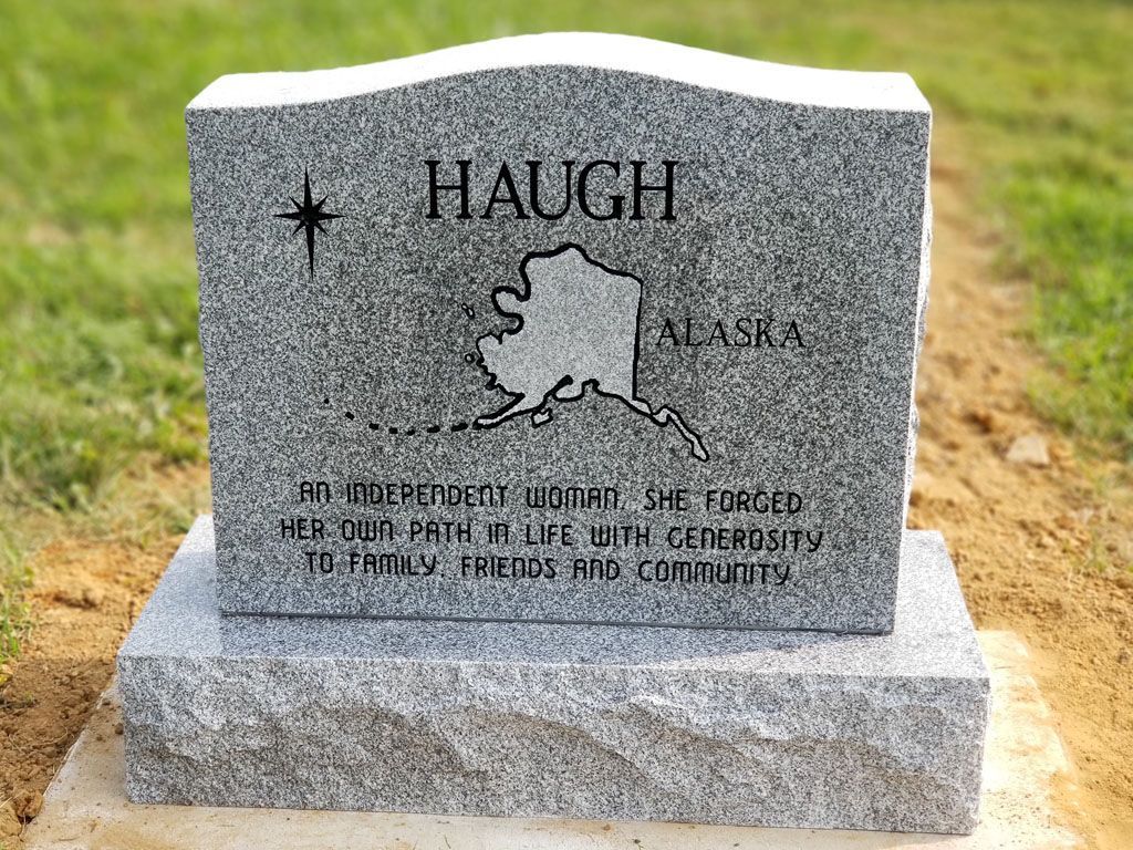 Gravestone for the Haugh family, gray granite with engraved state outline, set in a grassy cemetery.