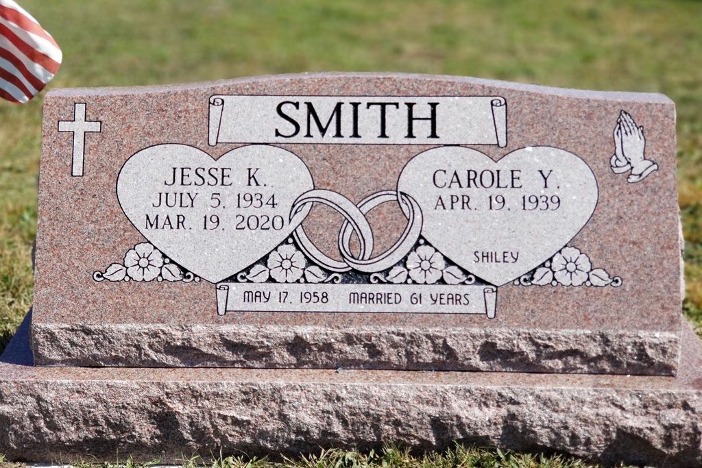 Smith family gravestone with engraved names, dates, and two heart designs in a cemetery lawn.