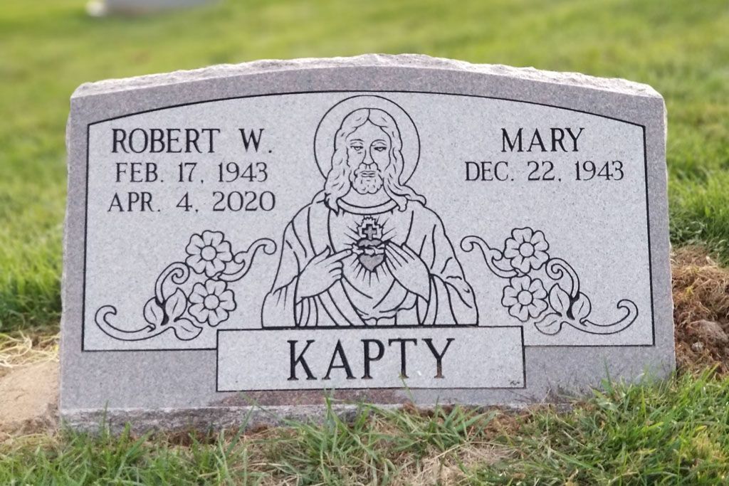 Gray memorial headstone with engraved portrait, flowers, and names Robert W. and Mary Karty