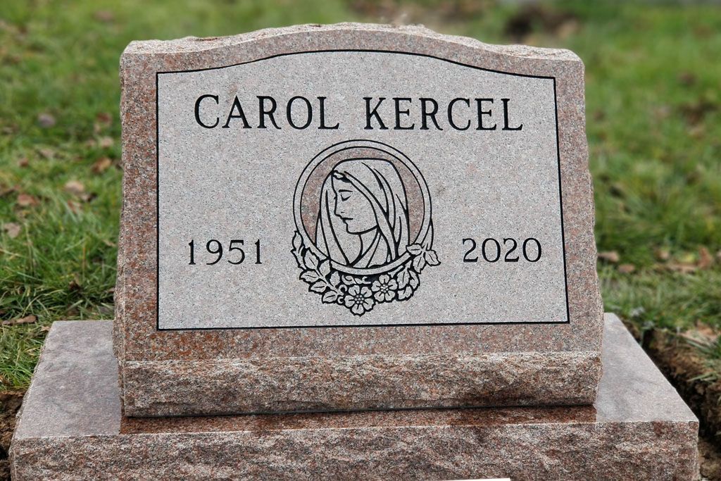 Gravestone for Carol Kercel, dated 1951–2020, with an etched emblem on a granite base.