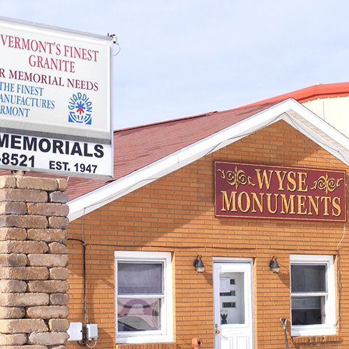 Orange storefronts for memorial and monument businesses with brick chimney and signs reading “Wyse Monuments” and “Memorials”