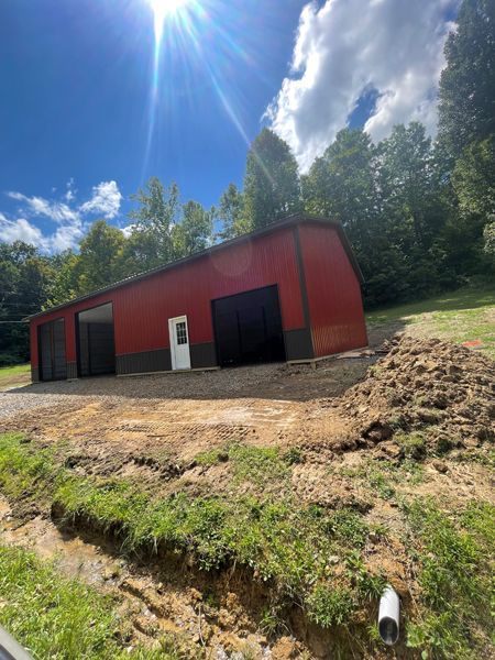 Red barn with black doors and white door, under a blue sky.
