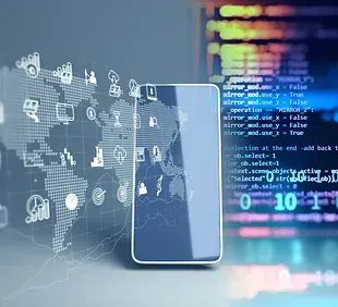 A smart phone is sitting on a table in front of a computer screen.
