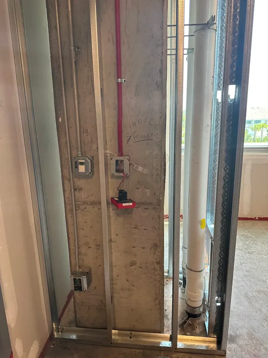 Construction in progress: Stud frame surrounding concrete column with electrical and plumbing elements.
