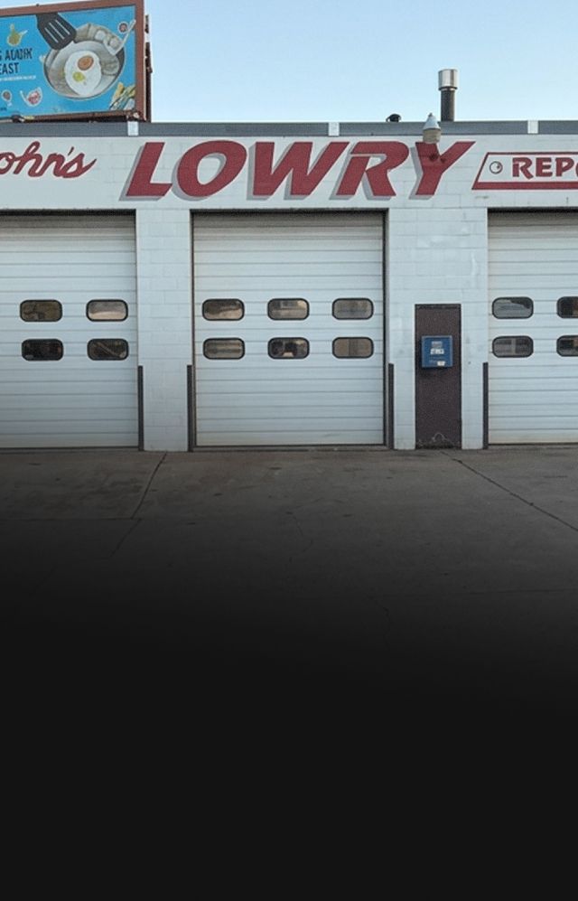 John’s Lowry auto service building with garage doors under a blue sky | Lowry Repair Center Inc