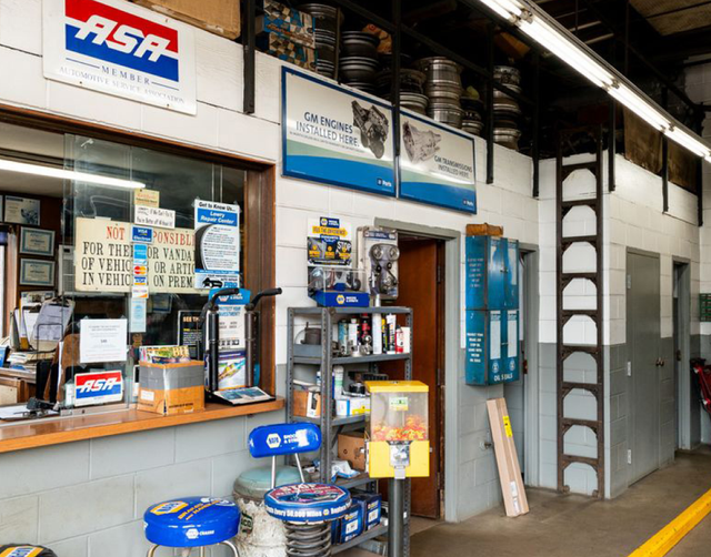 Convenience store counter with snacks, drinks, and a lottery display inside a narrow shop. | Lowry Repair Center Inc