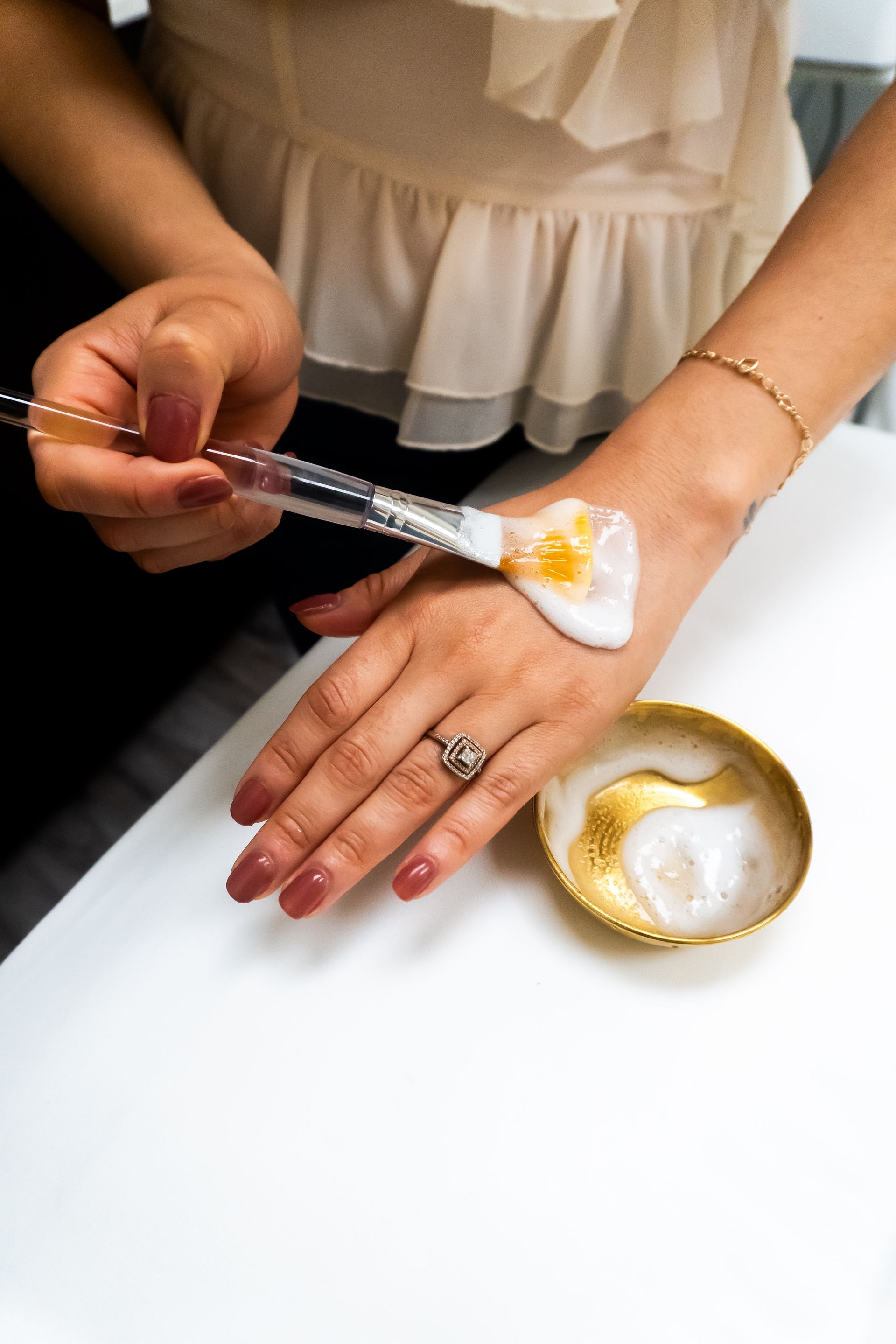 A woman is applying a cream to her hand with a brush.