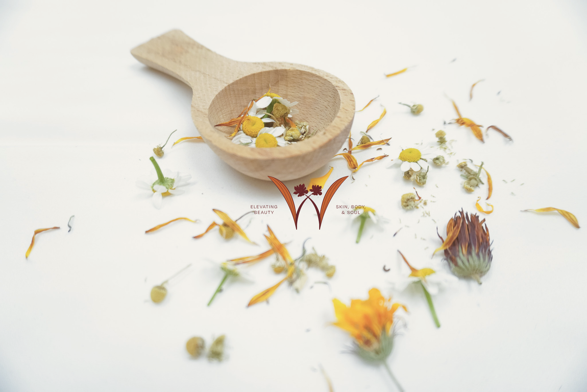 Wooden spoon with scattered dried flower petals on a white background