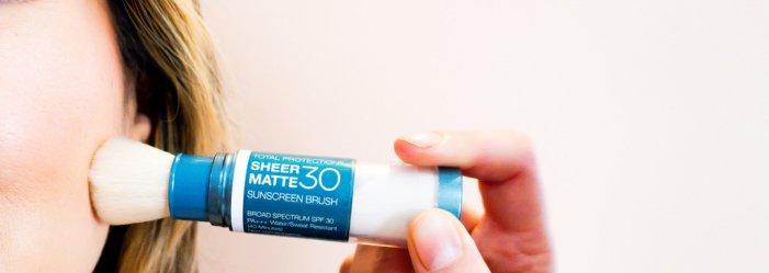 A person applying a sunscreen stick to their cheek; white background.