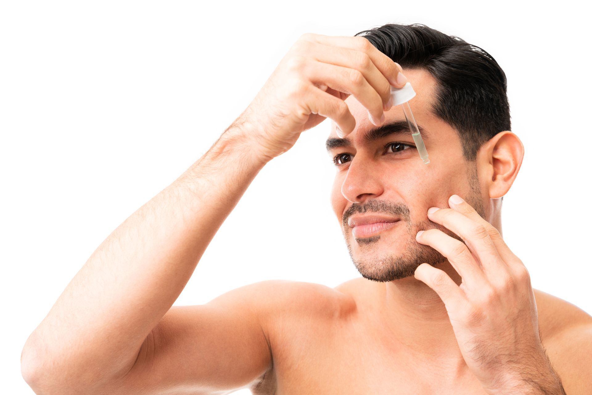 A shirtless man is applying lotion to his face.