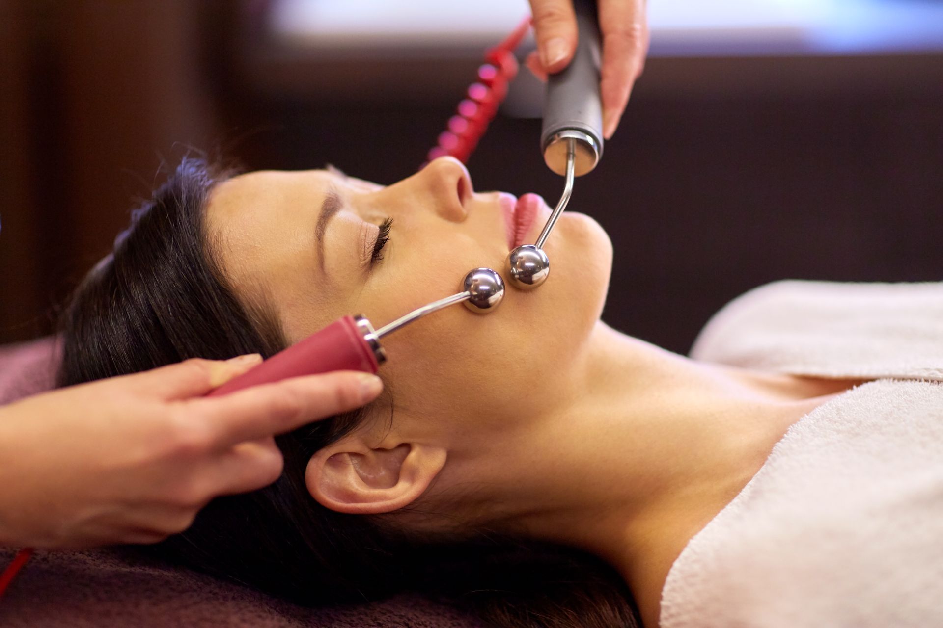 Person receiving a facial treatment with a handheld device in a spa setting