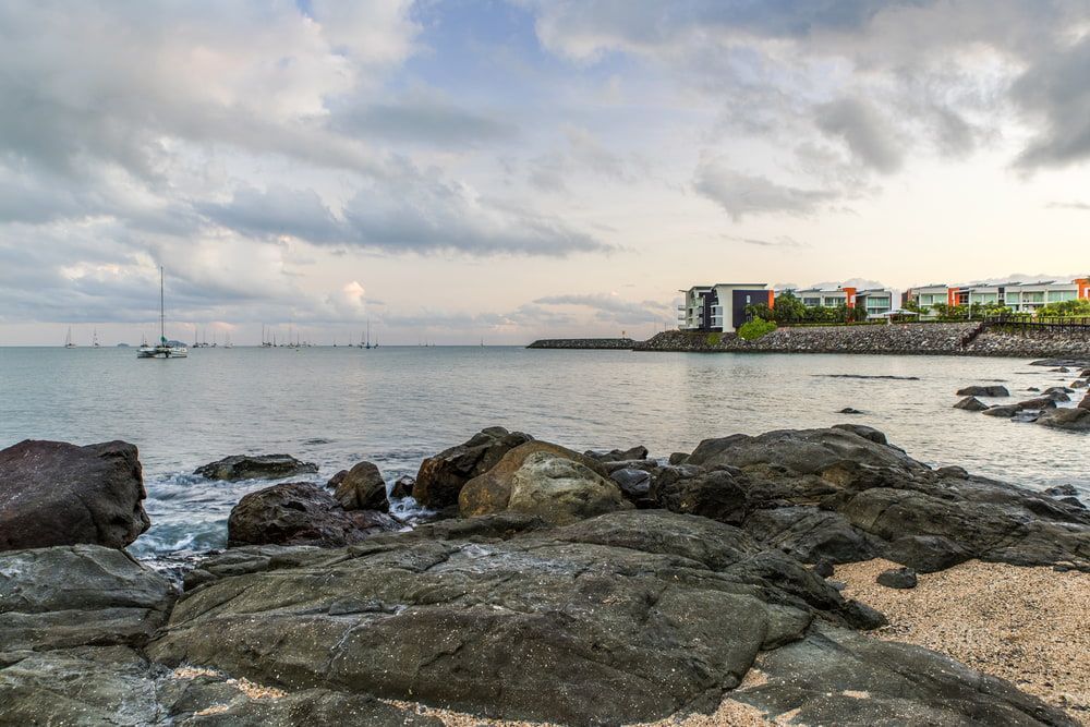 A Boat Is Floating On The Water Near A Rocky Shoreline — AMC Diesel Fuel Injection Services In Airlie Beach, QLD