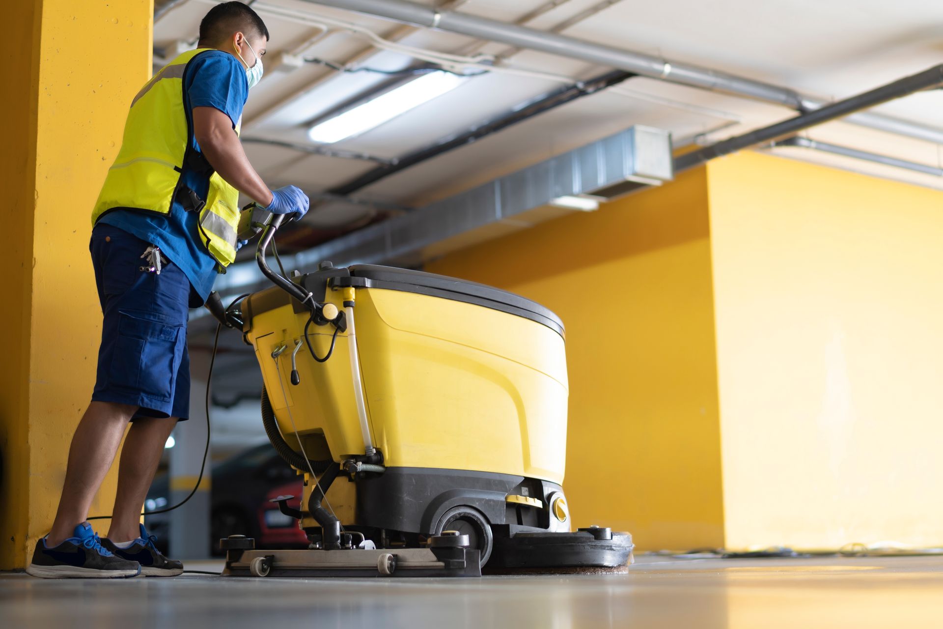 Worker in safety gear using a floor scrubber showcasing industrial cleaning solutions.