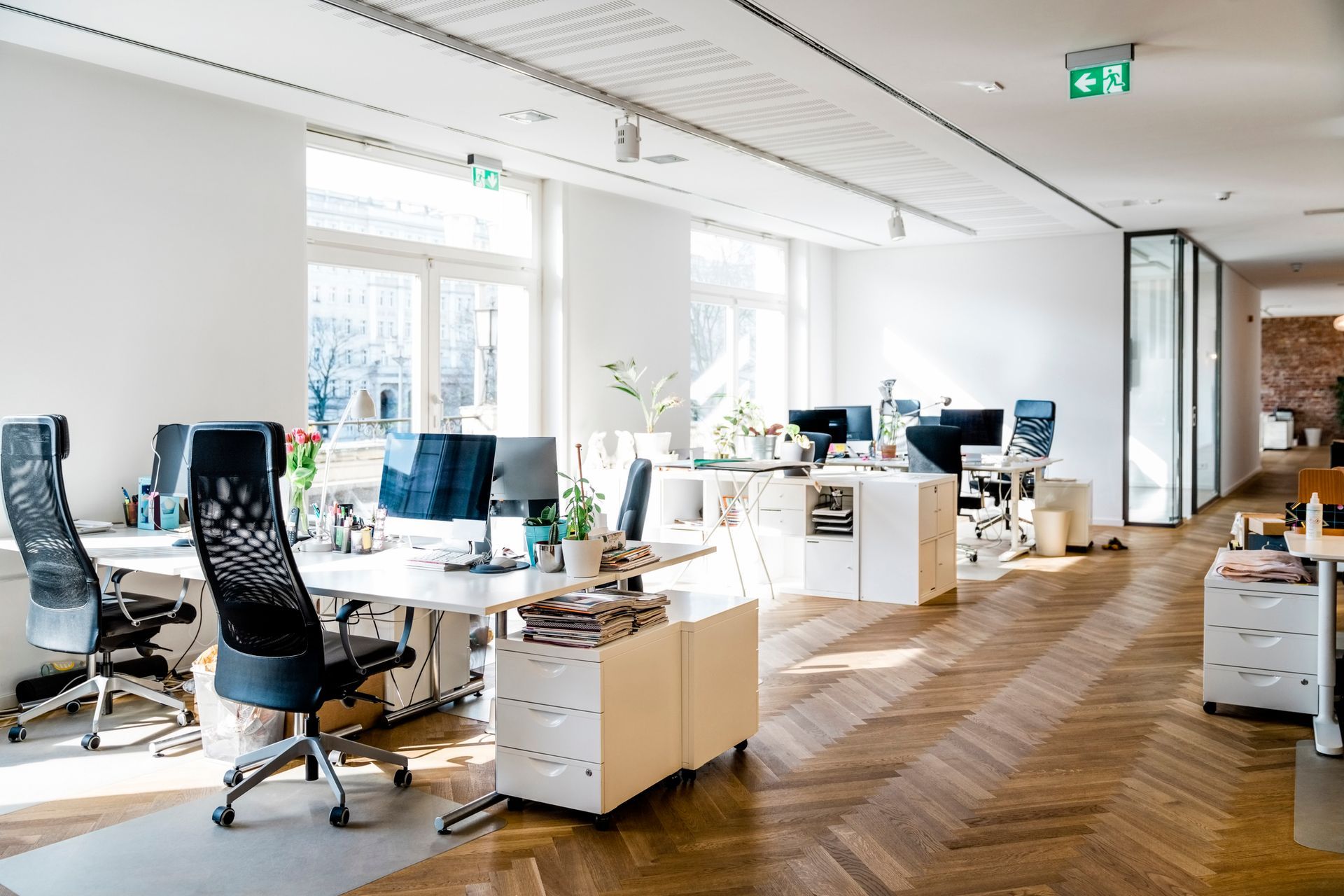 Open-plan office with desks, computers, and large windows.