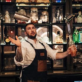 Bartender juggling shaker and bottle, bar setting.