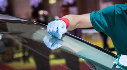 A person is cleaning the windshield of a car.