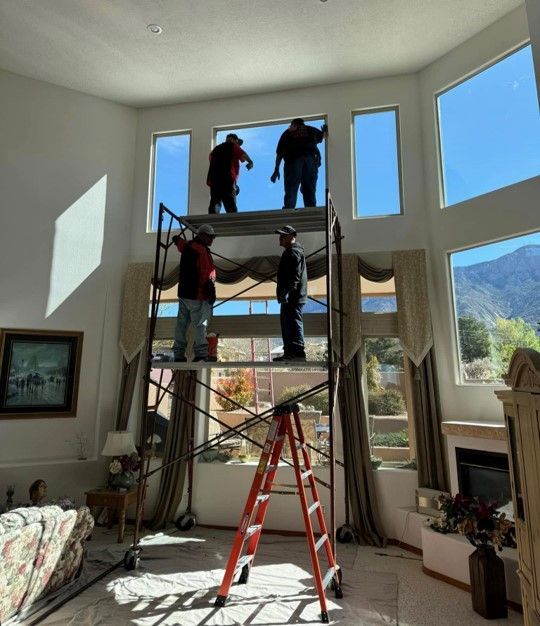 A group of people standing on a scaffolding in a living room — Auto Glass in Albuquerque, NM