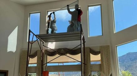 Two men are installing a window in a living room.— Auto Glass in Albuquerque, NM