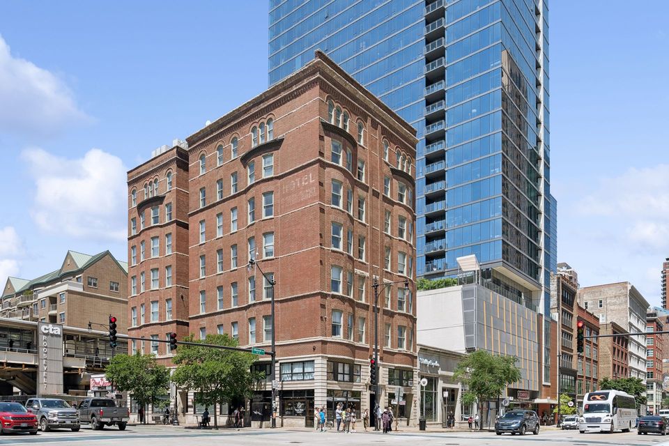 A large brick building is surrounded by tall buildings in a city.