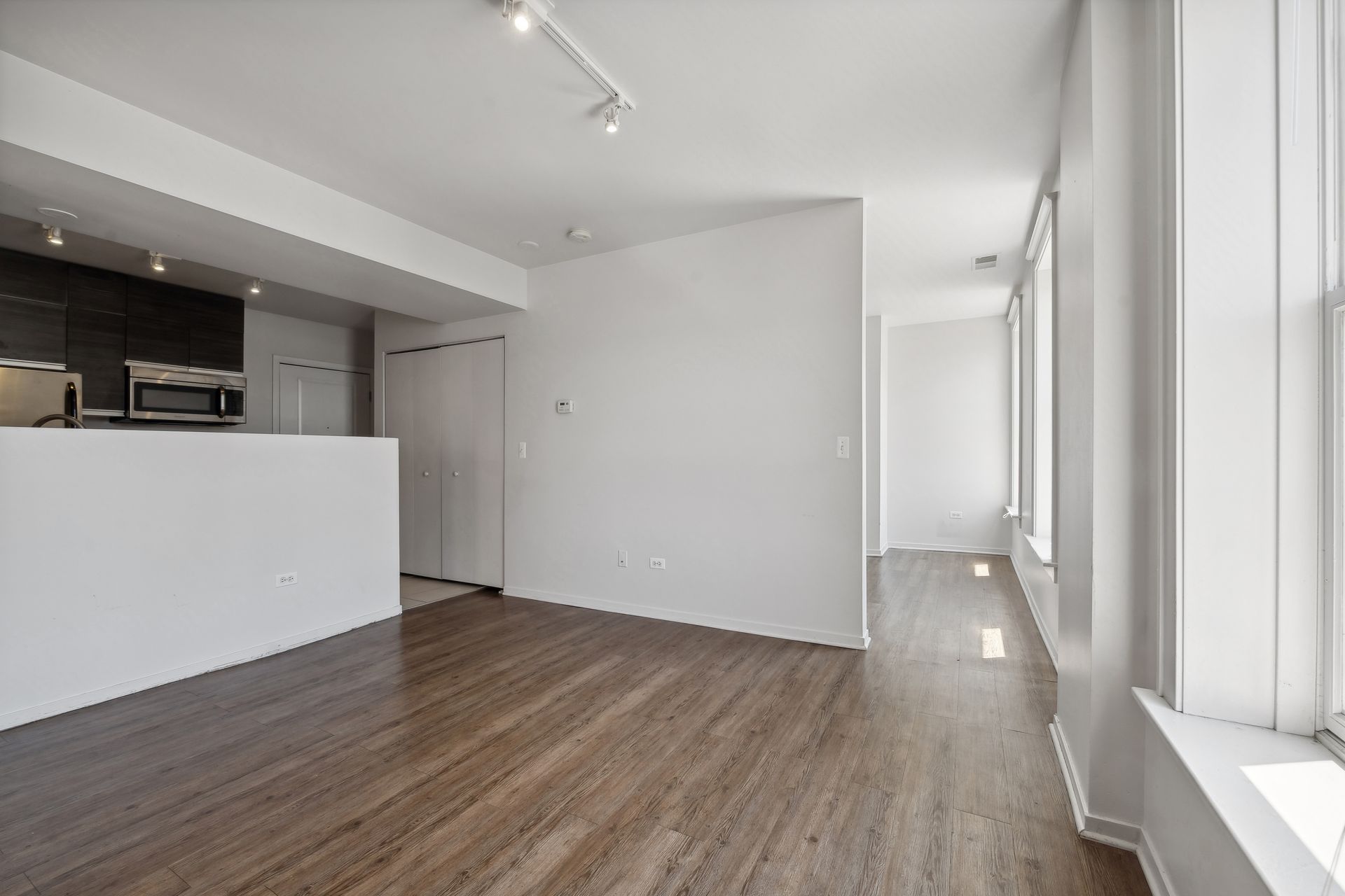 An empty living room with hardwood floors and white walls.