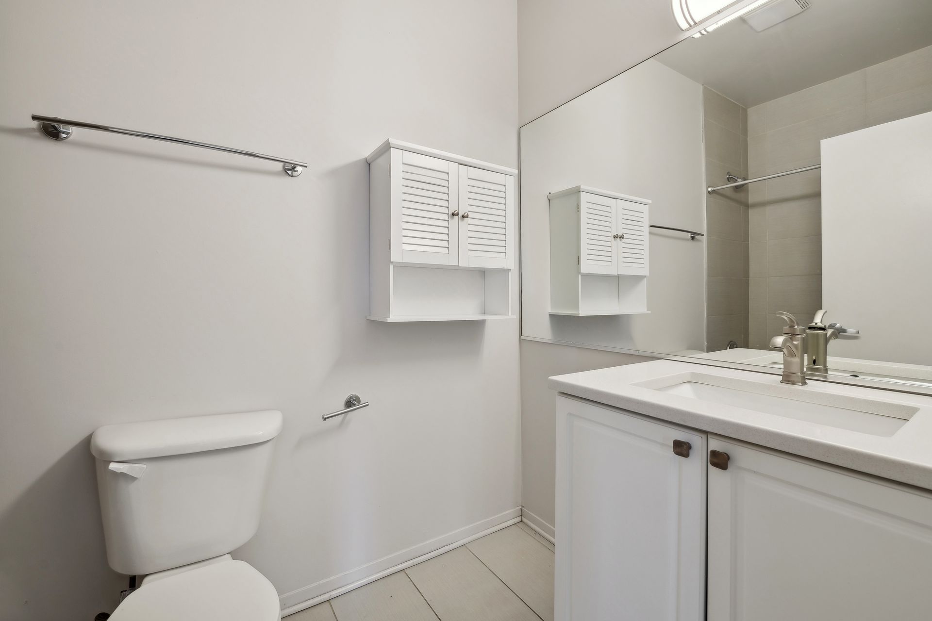 A bathroom with a toilet , sink and mirror.
