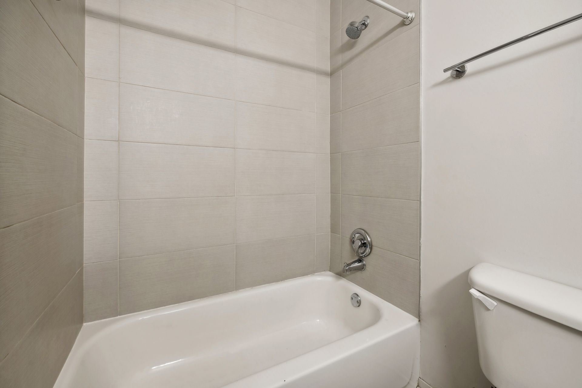 A bathroom with a bathtub , toilet and shower.