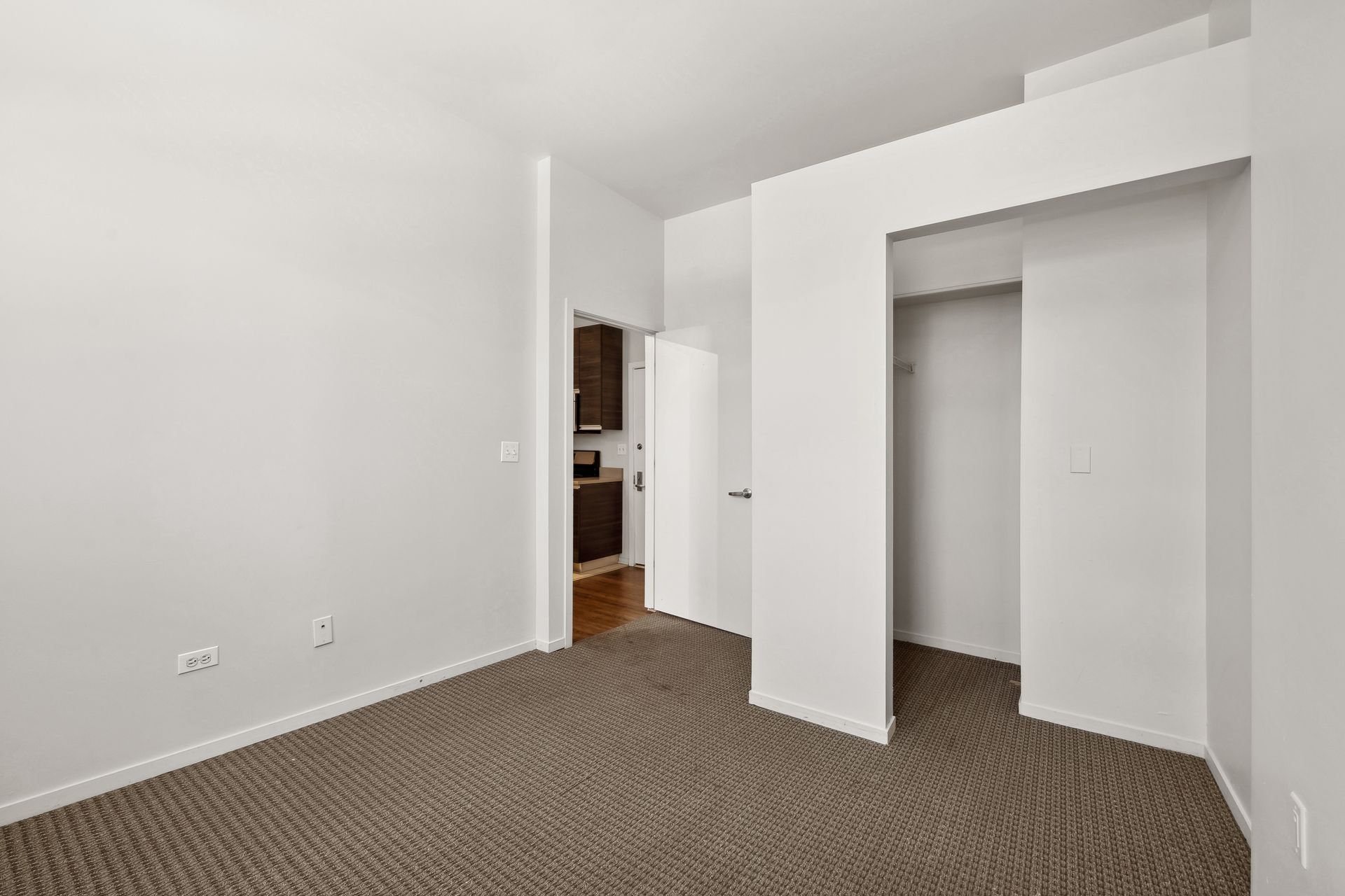 An empty room with a brown carpet and white walls.