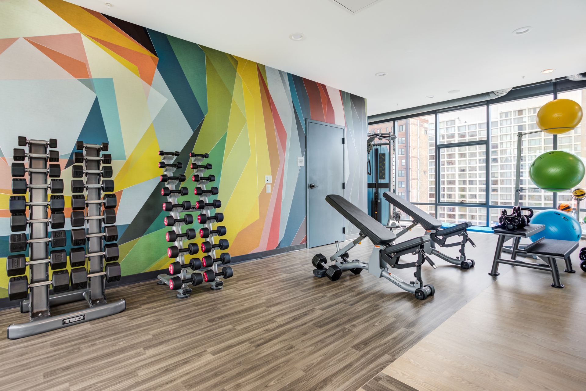 A gym with a mural on the wall and a bunch of dumbbells.