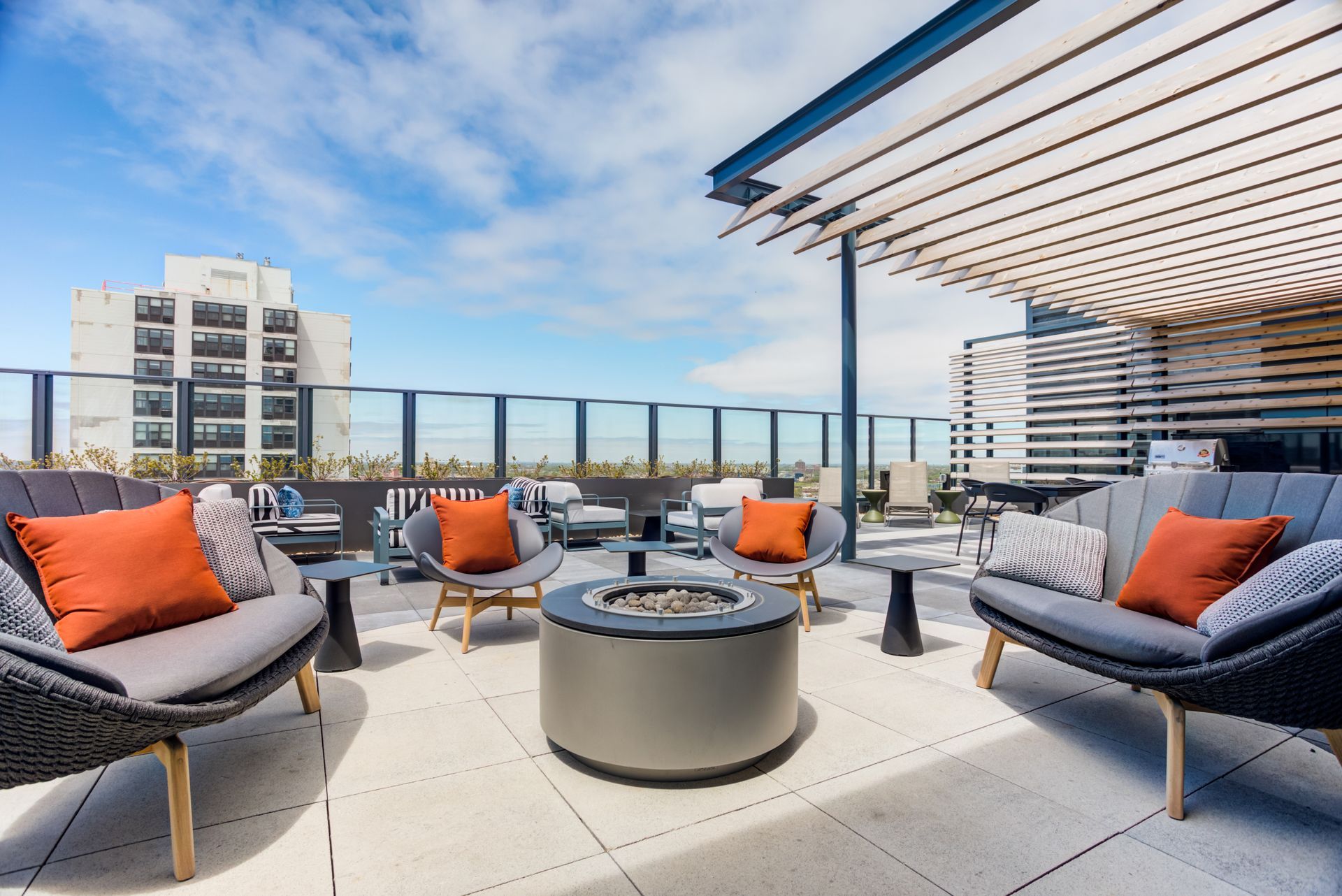 A patio with a fire pit , chairs , tables and a couch.