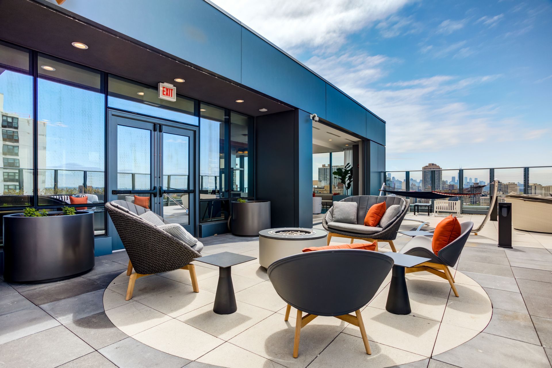 There are many chairs and tables on the roof of a building.