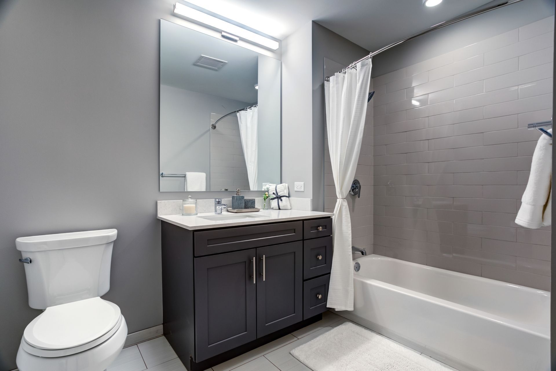 A bathroom with a toilet , sink , tub and mirror.
