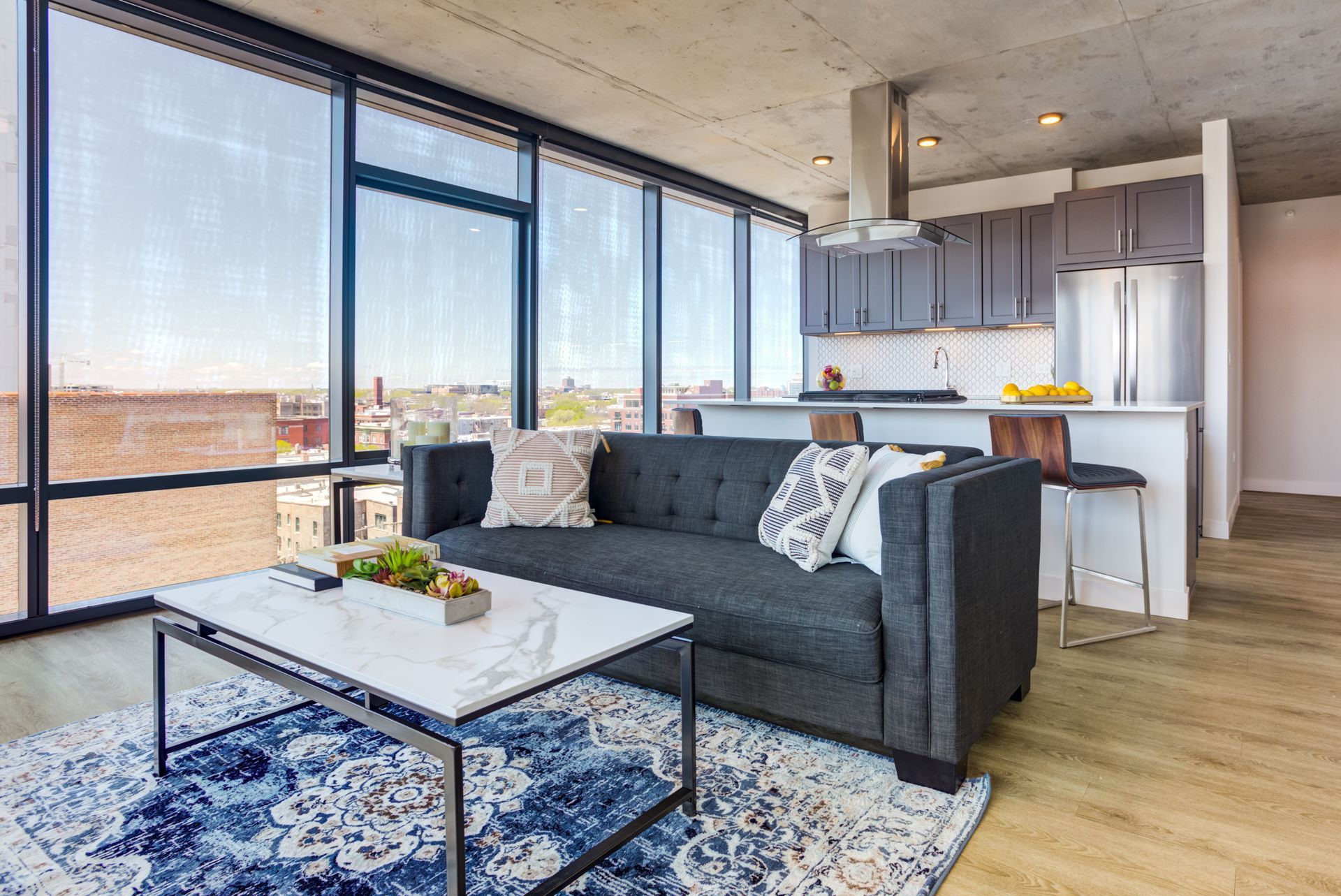 A living room with a couch , coffee table , and large windows.