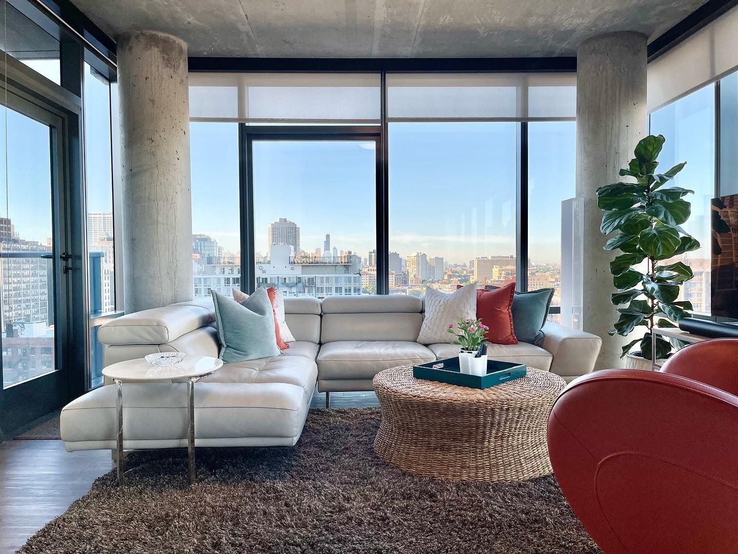 A living room with a couch , chair , coffee table and large windows.