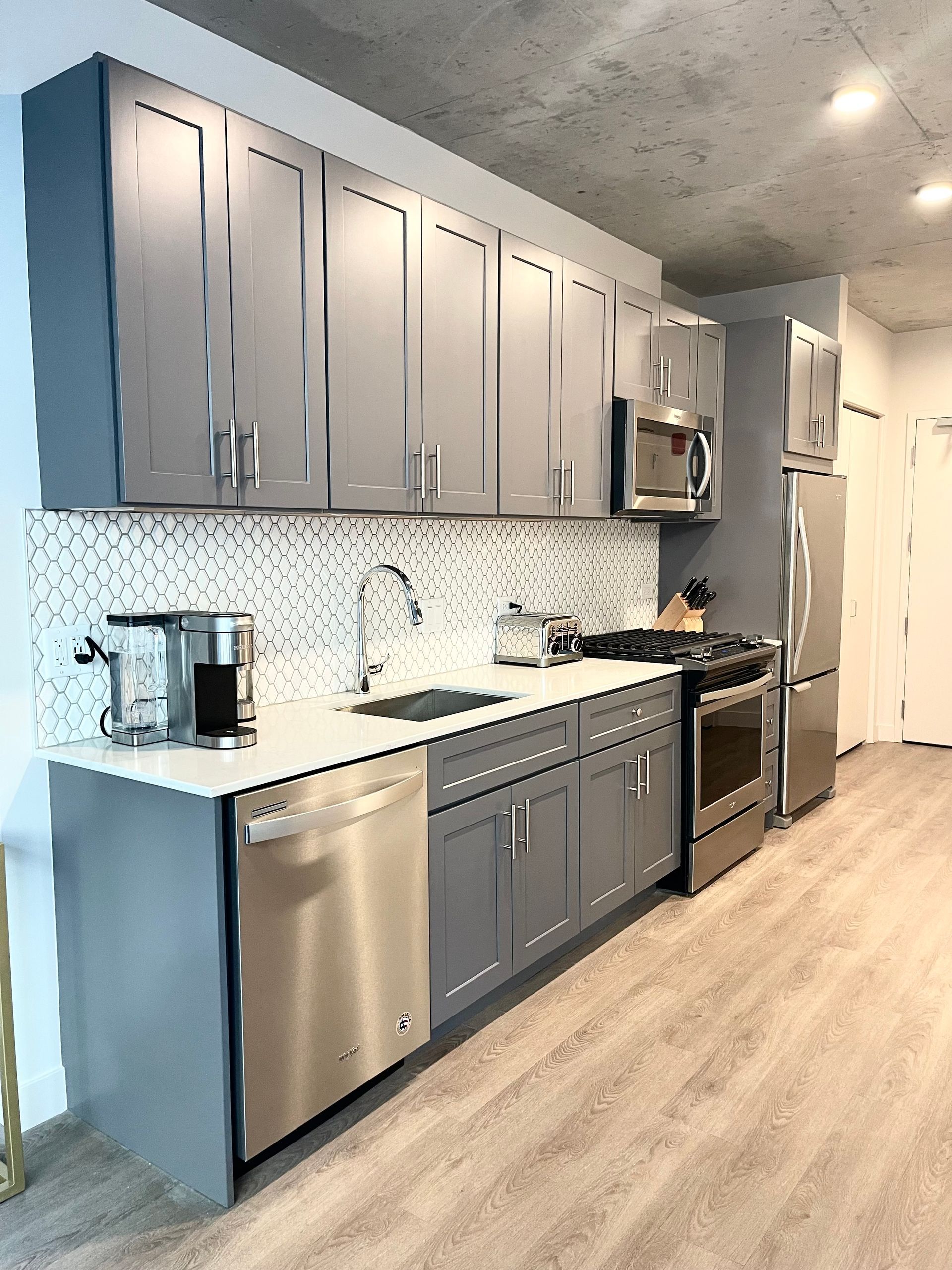 A kitchen with stainless steel appliances and gray cabinets