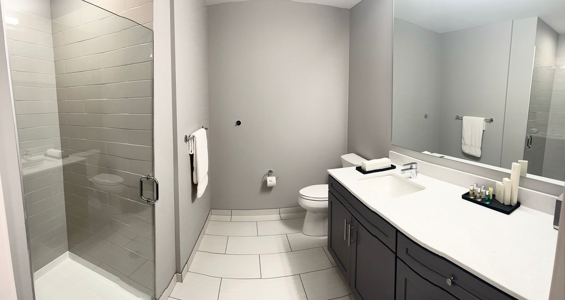A bathroom with a sink , toilet , shower and mirror.