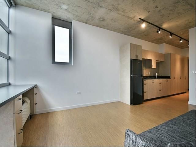 An empty room with a black refrigerator and a window
