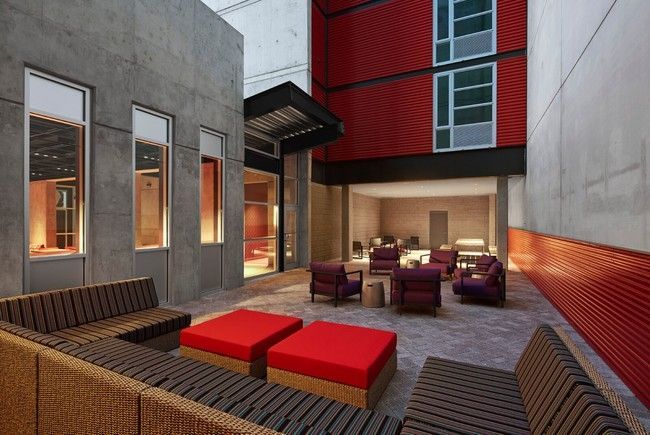 An artist 's impression of a courtyard with red chairs and ottomans