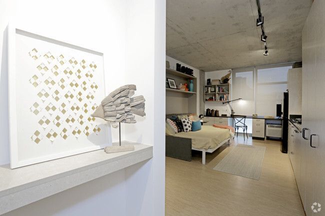 A bedroom with a couch , desk , and picture on the wall.