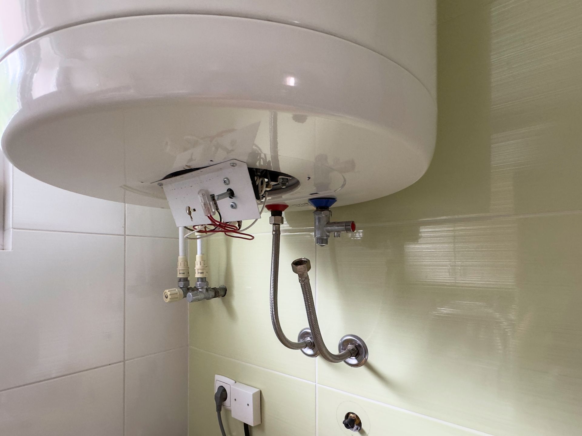 White Water Heater, Pipes, and Control Panel on a Tiled Wall — Full On Plumbing & Gas in Parap, NT