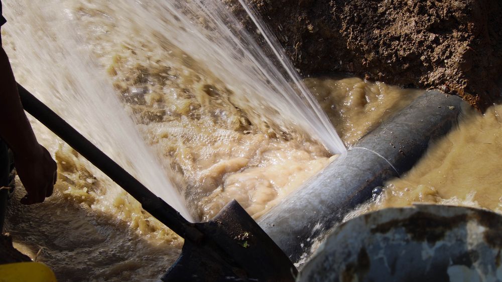 Pipe Gushing Water in a Muddy Ditch, With a Shovel Nearby — Full On Plumbing & Gas in Winnellie, NT