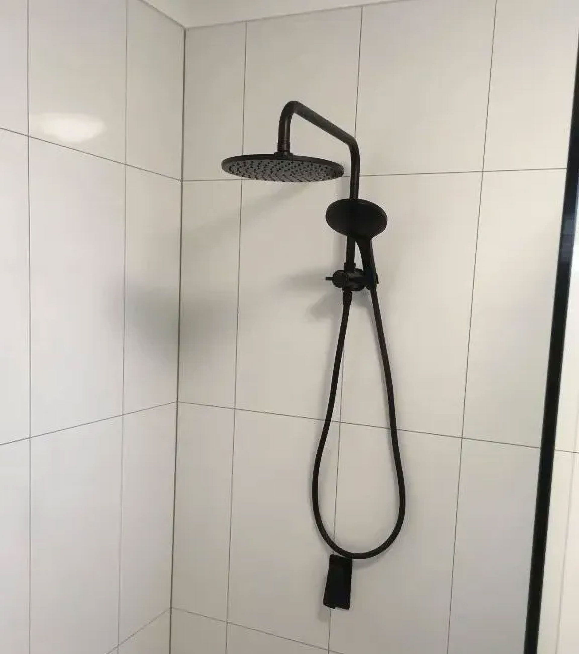 Black Showerhead and Handheld Shower Fixtures on White Tiled Wall — Full On Plumbing & Gas in Winnellie, NT