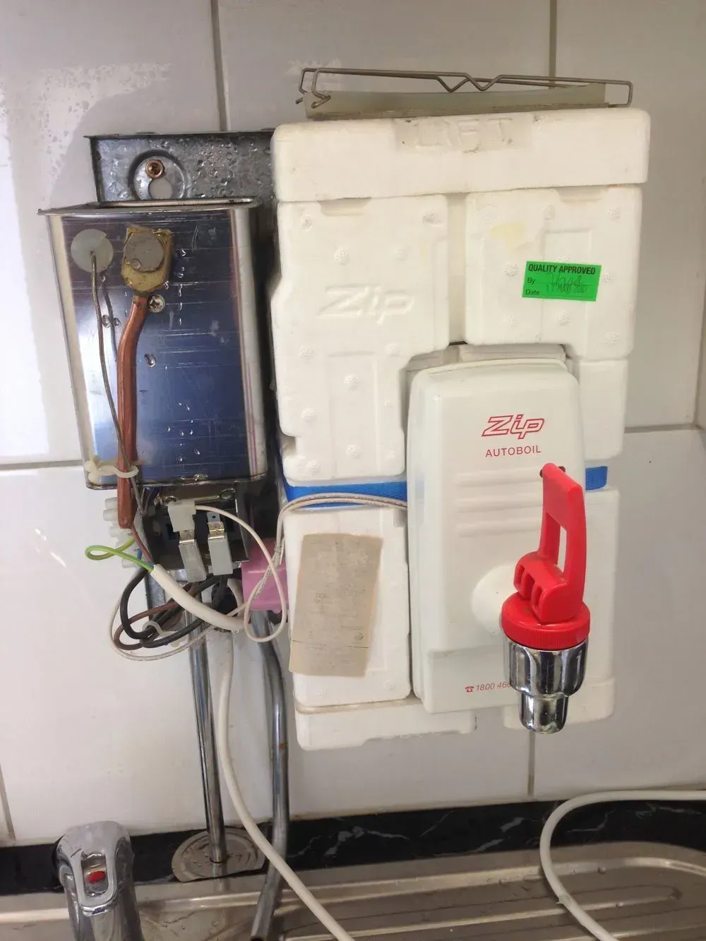 Wall-mounted Zip Water Heater With a Red Tap and Exposed Wiring on a Tiled Wall — Full On Plumbing & Gas in Winnellie, NT