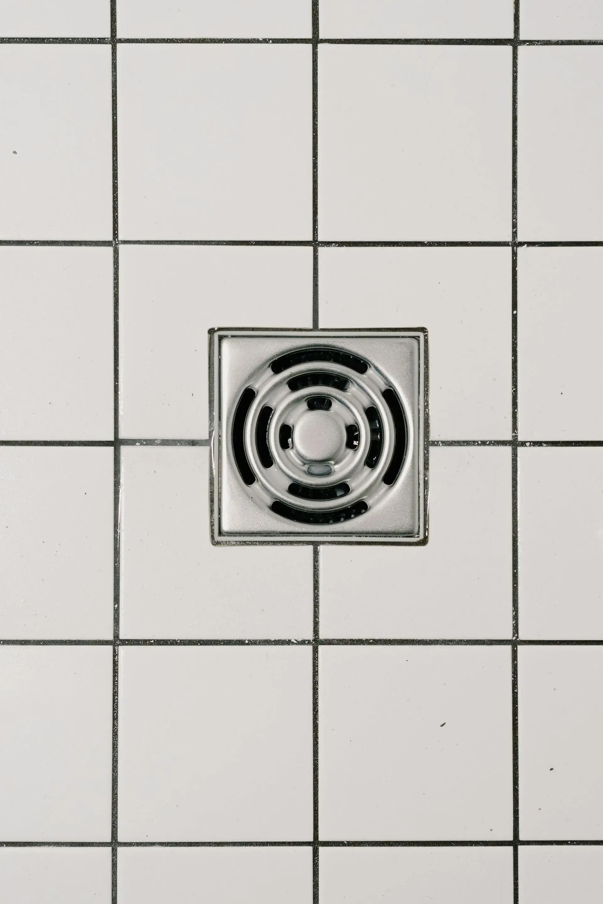 Square Shower Drain Surrounded by White Tiles With Dark Grout — Full On Plumbing & Gas in Winnellie, NT